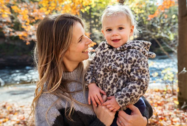 Little girl and her mother playing in the autumn park — Stock Photo, Image