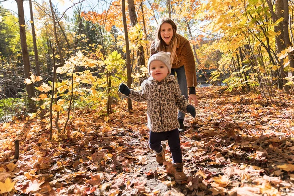 Kleines Mädchen und ihre Mutter spielen im Herbstpark — Stockfoto