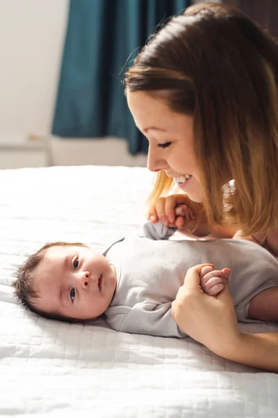 Mamá y bebé teniendo maravilloso tiempo en la cama en la mañana — Foto de Stock