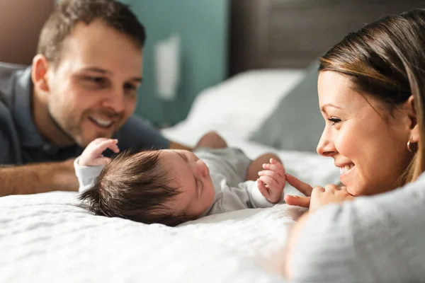 Una hermosa pareja con bebé recién nacido en la cama. — Foto de Stock