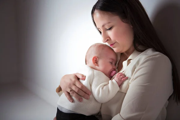 Jonge moeder met zijn dochter zitten op een witte verdieping studio, proberen te troosten — Stockfoto