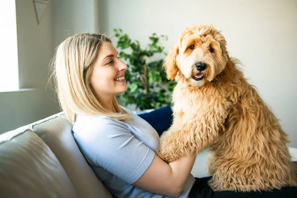 Vrouw met zijn gouden labradoodle hond thuis — Stockfoto