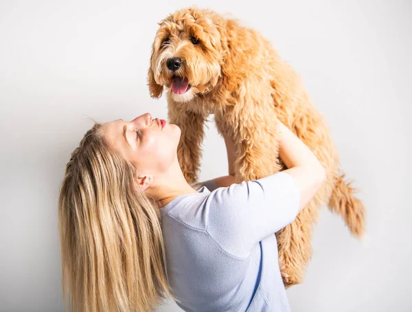 Kvinna med sin Golden Labradoodle hund isolerad på vit bakgrund — Stockfoto