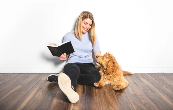 Žena s jeho Golden Labradoodle pes čtení knihy izolované na bílém pozadí — Stock fotografie