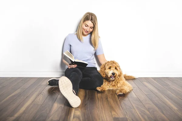 Žena s jeho Golden Labradoodle pes čtení knihy izolované na bílém pozadí — Stock fotografie