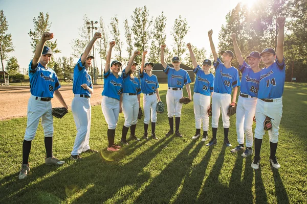 Группа бейсболистов, стоящих вместе на детской площадке с кулаком над головой — стоковое фото