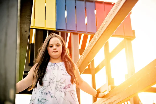 Ett porträtt av trisomie 21 vuxen flicka utanför vid solnedgången ha kul på en park — Stockfoto