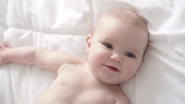 Menina bebê em roupa de cama branca em casa olhar agradável — Vídeo de Stock