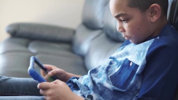 Ένα μαύρο αγόρι με tablet στο σαλόνι στο σπίτι — Αρχείο Βίντεο