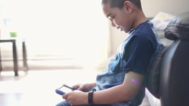 Een zwarte jongen met tablet in de woonkamer thuis — Stockvideo