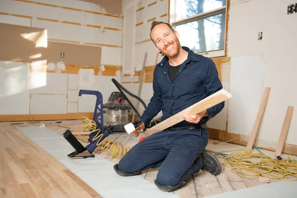 Мужчина-рабочий устанавливает деревянный пол в доме — стоковое фото