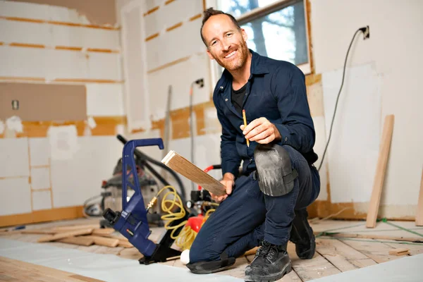 Un trabajador masculino instala piso de madera en una casa —  Fotos de Stock