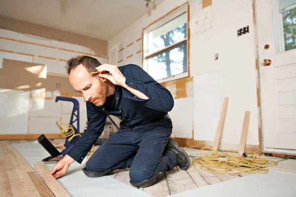 Чоловік працівник встановлює дерев'яну підлогу на будинок — стокове фото