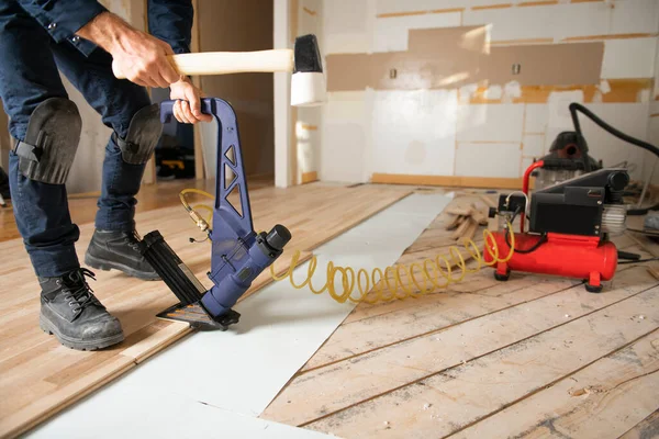 男性労働者が家に木の床を設置する — ストック写真