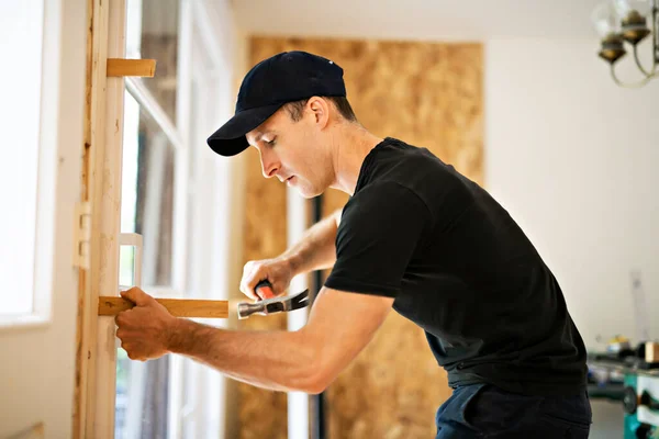 Un joven guapo instalando la puerta corredera doble del patio en una nueva obra de construcción de la casa —  Fotos de Stock