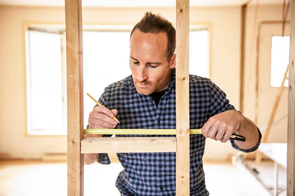 Un trabajador en el taller de carpintería renovación usando cinta adhesiva —  Fotos de Stock