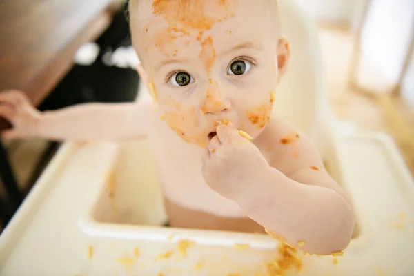 Un pequeño bebé comiendo su cena y haciendo un lío — Foto de Stock