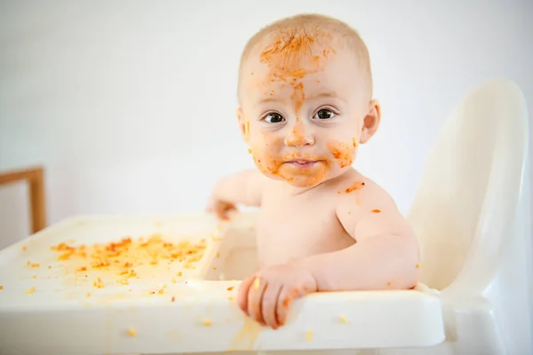 Un pequeño bebé comiendo su cena y haciendo un lío — Foto de Stock