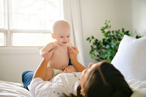 Uma mãe e um bebê na cama se divertindo — Fotografia de Stock