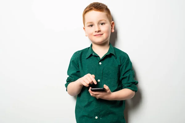 Foto conceptual de un niño enviando mensajes en su teléfono celular en un estudio —  Fotos de Stock