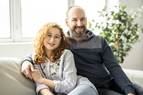 Alegre pelirroja padre e hija sonriendo a cámara en sofá — Foto de Stock