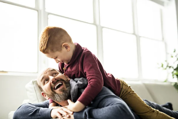 Padre con niña pelirroja divirtiéndose en el sofá en casa — Foto de Stock