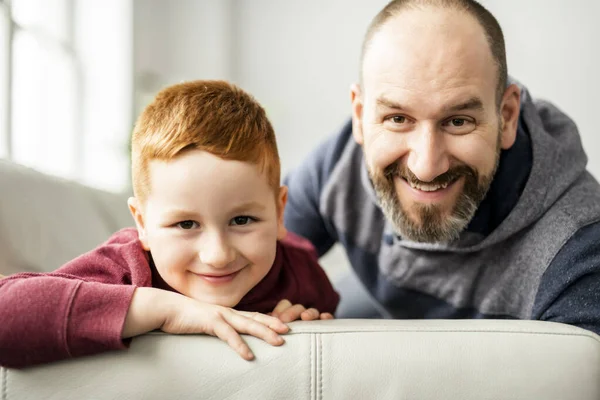 赤い頭の子供を持つお父さん家でソファで楽しんで — ストック写真