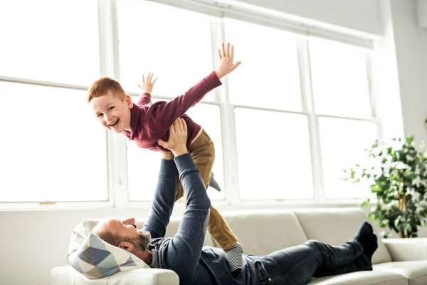 Батько з рудою дитиною розважається на дивані вдома — стокове фото