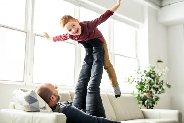 Padre con niña pelirroja divirtiéndose en el sofá en casa — Foto de Stock