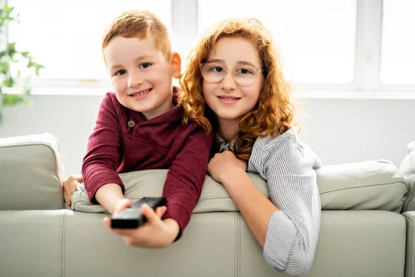 Щаслива дівчина і хлопчик дивиться телевізор з пультом — стокове фото