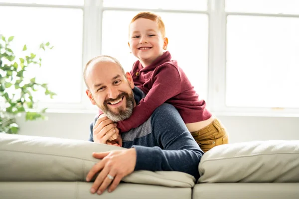 Ojciec z rudym dzieckiem siedzi na kanapie w domu — Zdjęcie stockowe