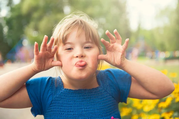 Portrét trisomie 21 dítě dívka venku baví v parku dává nějaké ponuré — Stock fotografie