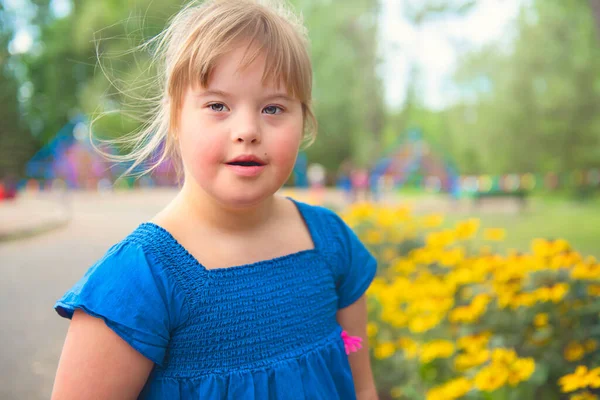 Um retrato de trissomia 21 criança menina fora se divertindo em um parque — Fotografia de Stock