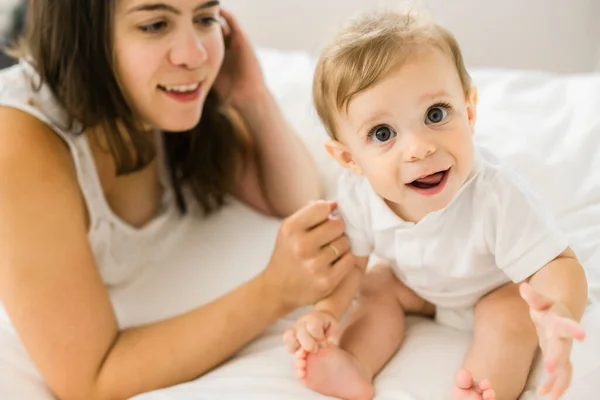 Uma mãe e um bebê na cama se divertindo — Fotografia de Stock