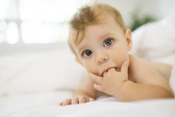 小さな赤ちゃんが白い寝室で指を吸って — ストック写真