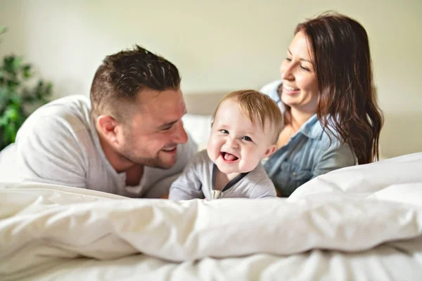 Счастливая семья мать, отец и сын дома в постели — стоковое фото