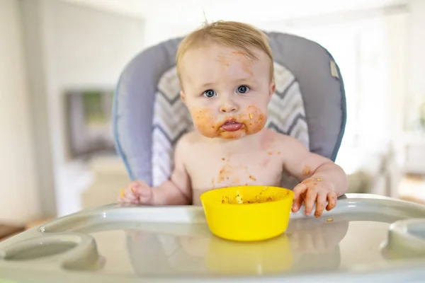 Een kleine baby eet haar eten en maakt er een puinhoop van. — Stockfoto