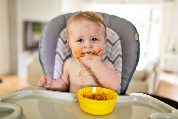 Een kleine baby eet haar eten en maakt er een puinhoop van. — Stockfoto