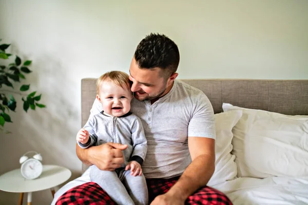 Un padre con un lindo hijo bebé en la cama en casa — Foto de Stock