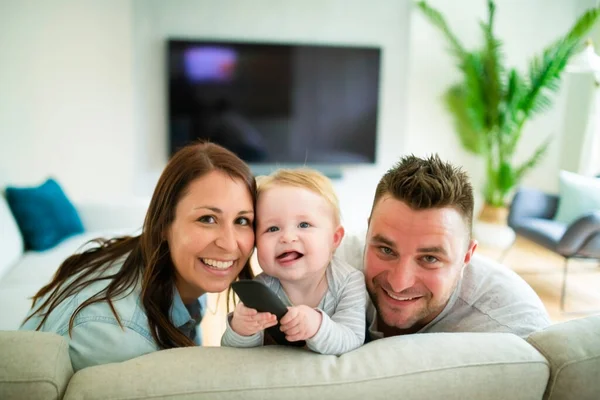 Rodina se dívá na televizi doma na gauči — Stock fotografie