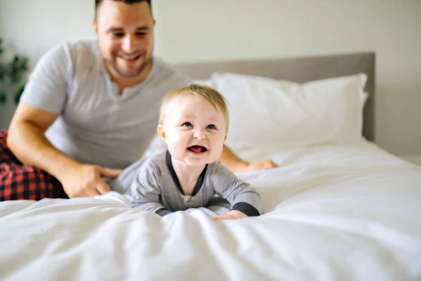 Un padre con un lindo hijo bebé en la cama en casa — Foto de Stock