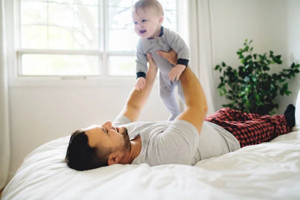 Un padre con un lindo hijo bebé en la cama en casa —  Fotos de Stock