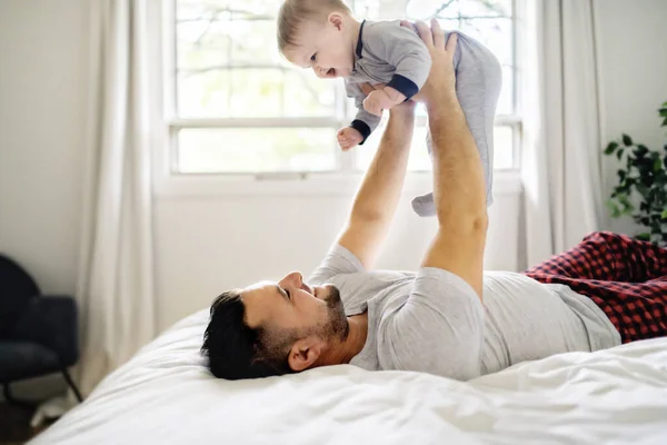 Un padre con un lindo hijo bebé en la cama en casa — Foto de Stock