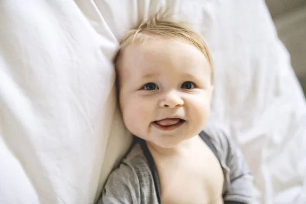 Un bambino carino in biancheria da letto bianca a casa — Foto Stock