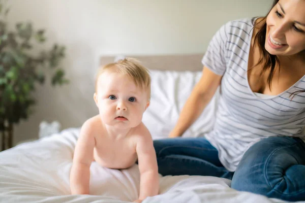 Mother and child on a white bed playing in sunny bedroom — Stock Photo, Image