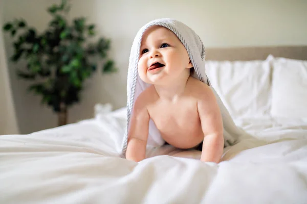 Un lindo bebé en ropa de cama blanca en casa — Foto de Stock