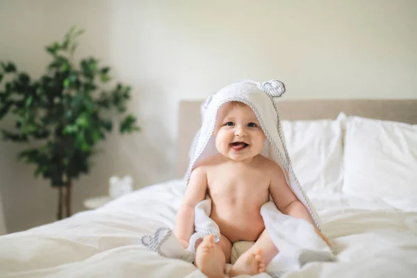 Un lindo bebé en ropa de cama blanca en casa — Foto de Stock