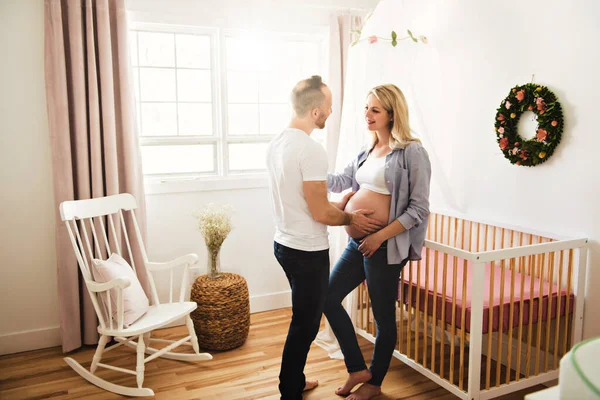Беременная мать и ее муж в детской комнате дома — стоковое фото