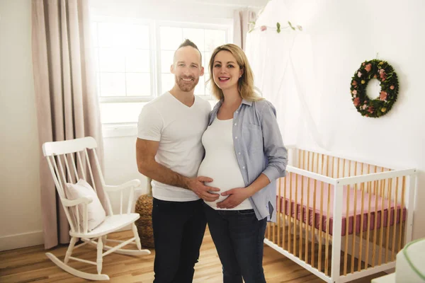 Těhotná matka a její manžel na dětském pokoji doma — Stock fotografie