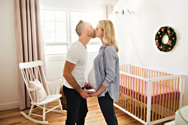 Беременная мать и ее муж в детской комнате дома — стоковое фото